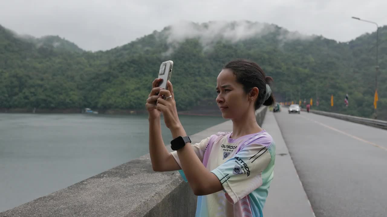 一名女子正在用智能手机拍摄美丽的景色。视频下载