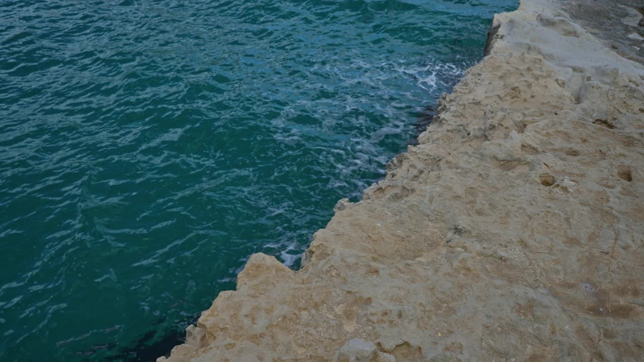 在意大利普利亚州萨伦托的torre dell'orso，绿松石般的海浪轻轻地撞击着崎岖的岩石悬崖，展示了这个标志性的欧洲景观的自然海岸之美。视频素材