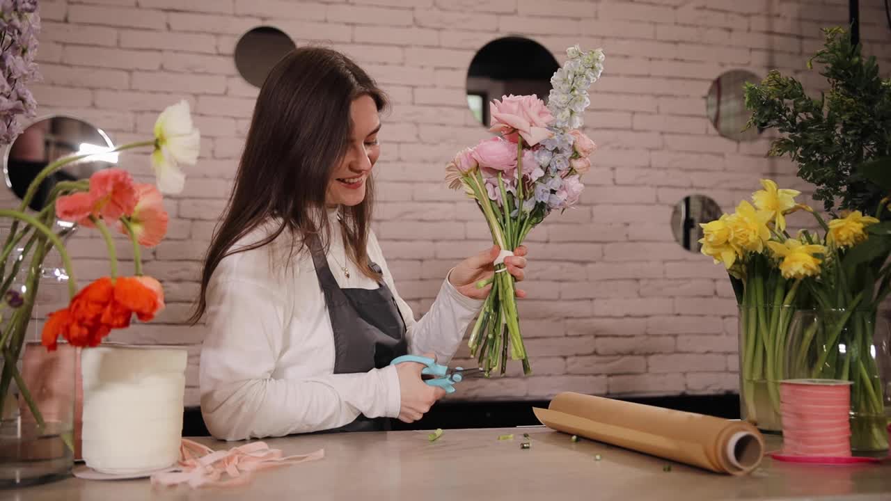 白种女花匠在花店工作场所制作花束前，用剪刀剪下插花和绿色植物。专业制作花店新鲜花束。小型企业视频下载