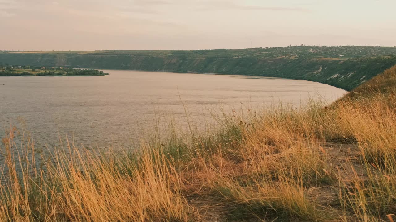 这令人惊叹的场景是一条河流在郁郁葱葱的草山中弯曲，沐浴在金色日落的温暖光线中视频素材