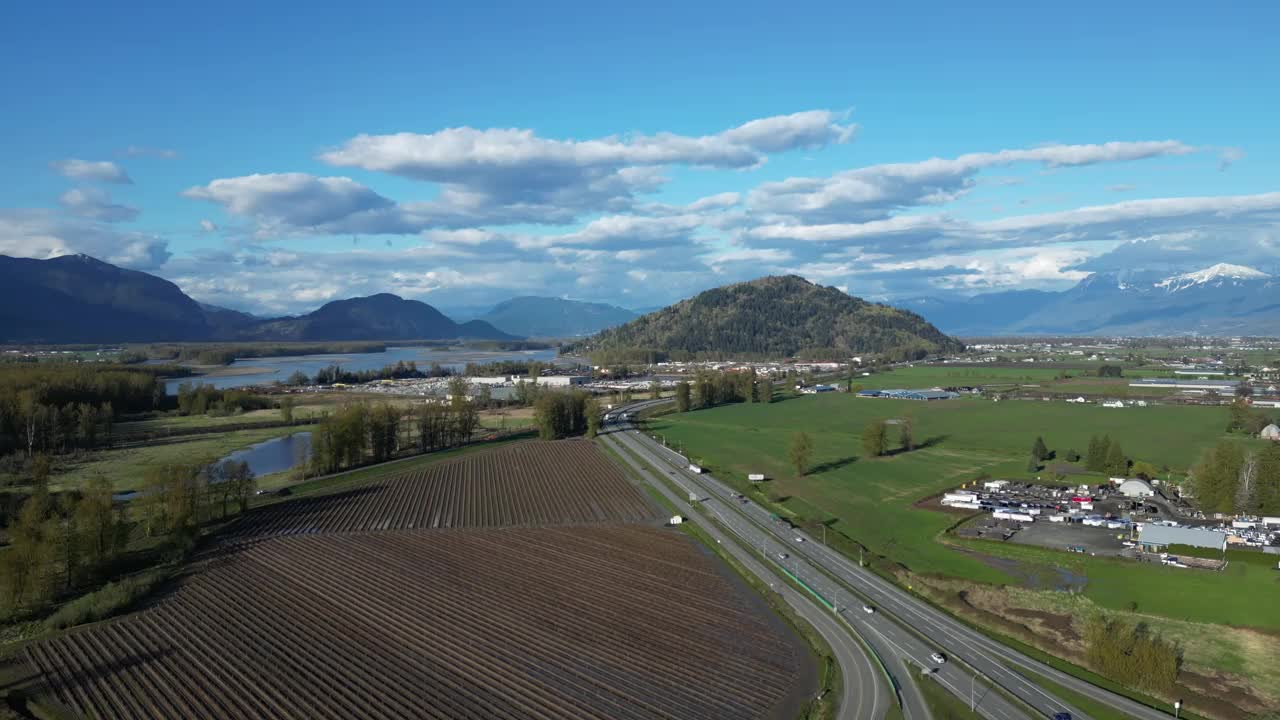 风景优美的高速公路被农田、城市和山脉环绕。蓝天多云，天晴。夏天。弗雷泽山谷，不列颠哥伦比亚省，加拿大。视频下载