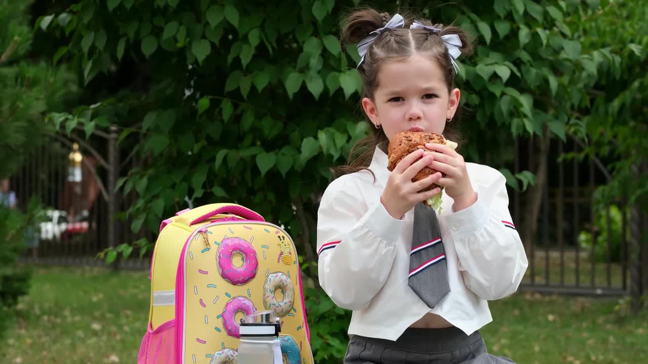 学校的午餐，一个男学生在街上吃一个汉堡包，一个孩子在上学前吃一个三明治，一个男学生的快餐视频下载