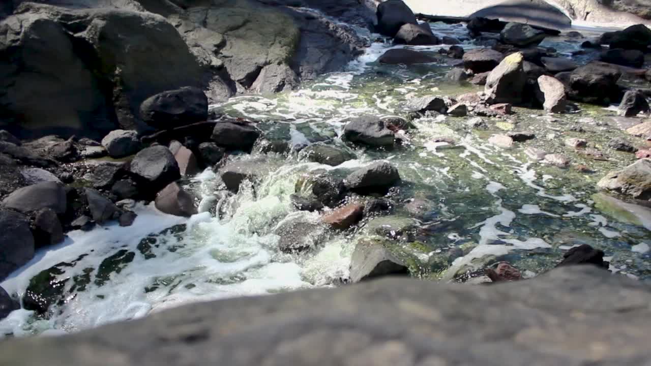 瀑布从火山口流出，水流在岩石上视频下载