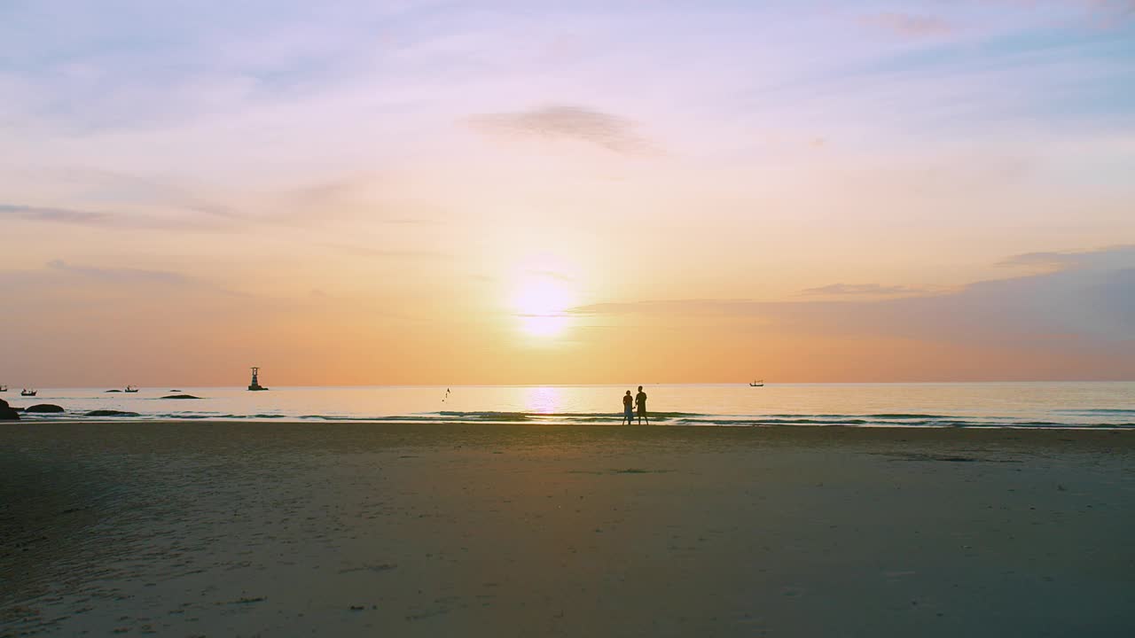 一个宁静的海滩景观，宁静的日落在海上与家人享受时刻海浪在背景，他们的剪影在金色的天空，传达自由与和平的感觉视频素材