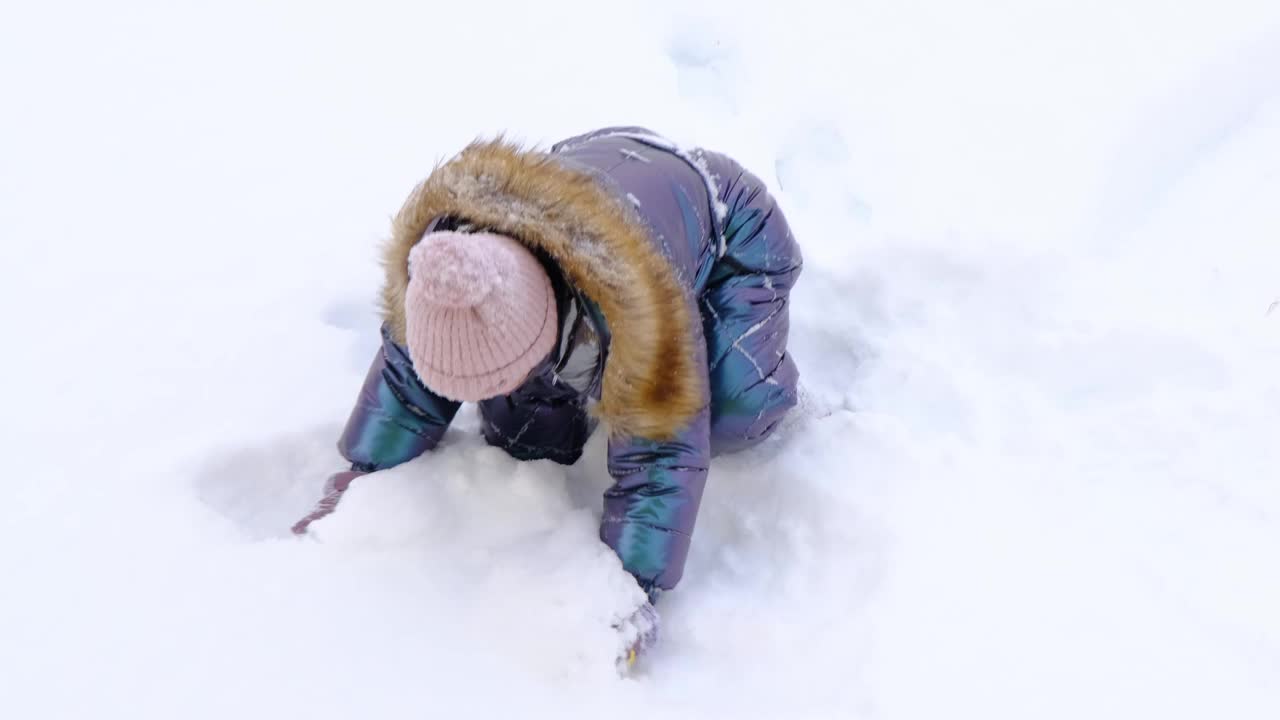 一个穿着蓝色连体衣的女孩高兴地抛起了雪。冬季乐趣，户外游戏，圣诞节视频下载