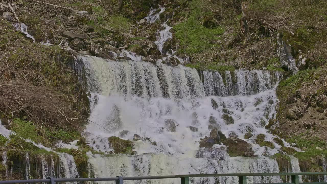 瀑布在山间，桥的旁边。水从瀑布倾泻而下。格拉鲁斯州内菲尔斯附近的Rauti瀑布视频素材