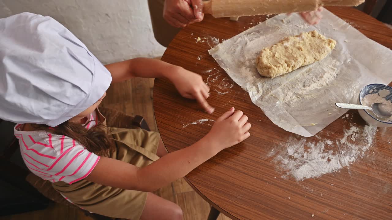 孩子和大人一起烘焙，在厨房的木桌上揉面视频素材