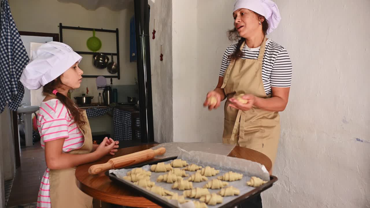 母女俩穿着围裙，戴着厨师帽，在厨房里一起烘焙视频素材