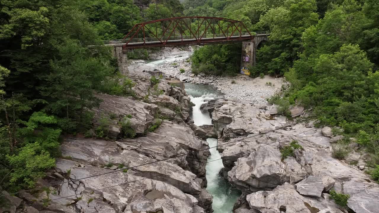 俯瞰一座桥，横跨瑞士泰辛的马吉阿塔尔山谷的一条多山河流。工程概念与大自然的崎岖之美和高山景观和谐共存。视频素材