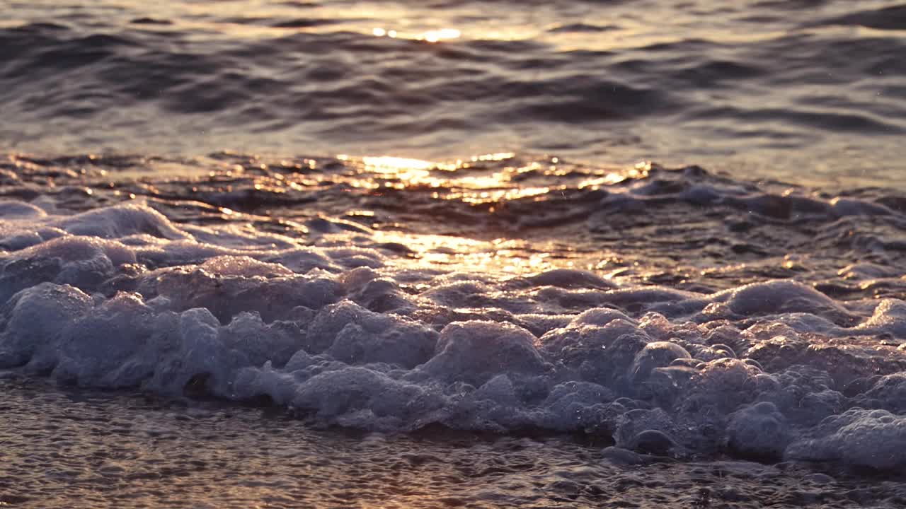 慢动作，海浪和海泡沫打破沙滩海岸线在夏季日出，美丽的金色阳光，通过水，120 fps 4k镜头视频下载