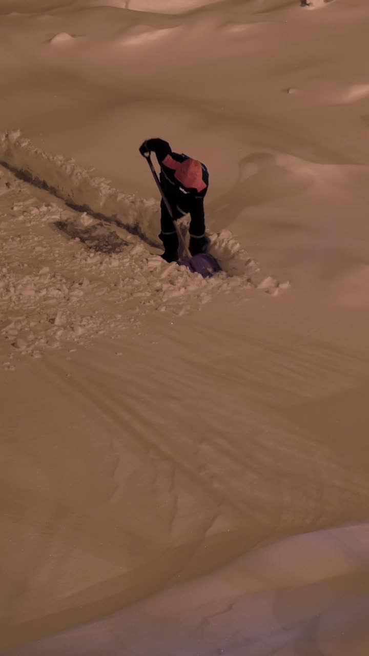 图为，在大雪中，工人们在夜间勤劳地铲雪，展现了在冬季保持清洁安全的工作环境所需要的不懈努力。垂直视频视频素材