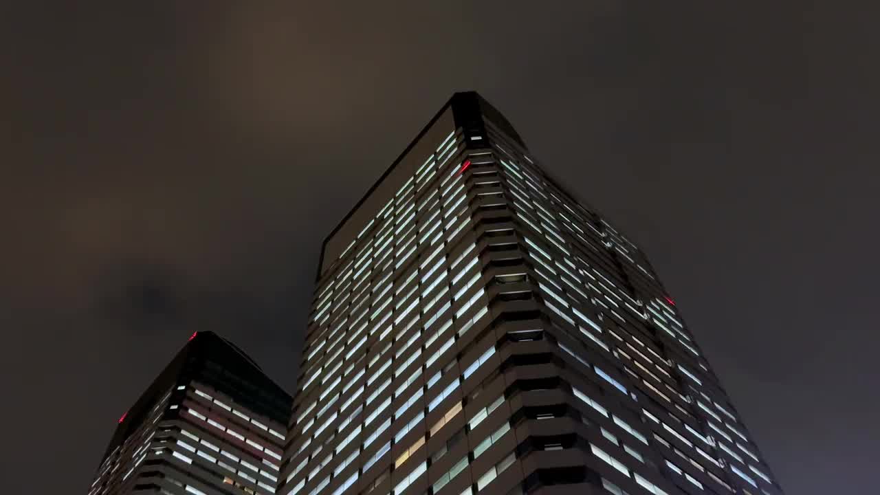 在东京晴美地区，摩天大楼在暴风雨的夜空下闪闪发光，远处传来雷声视频素材