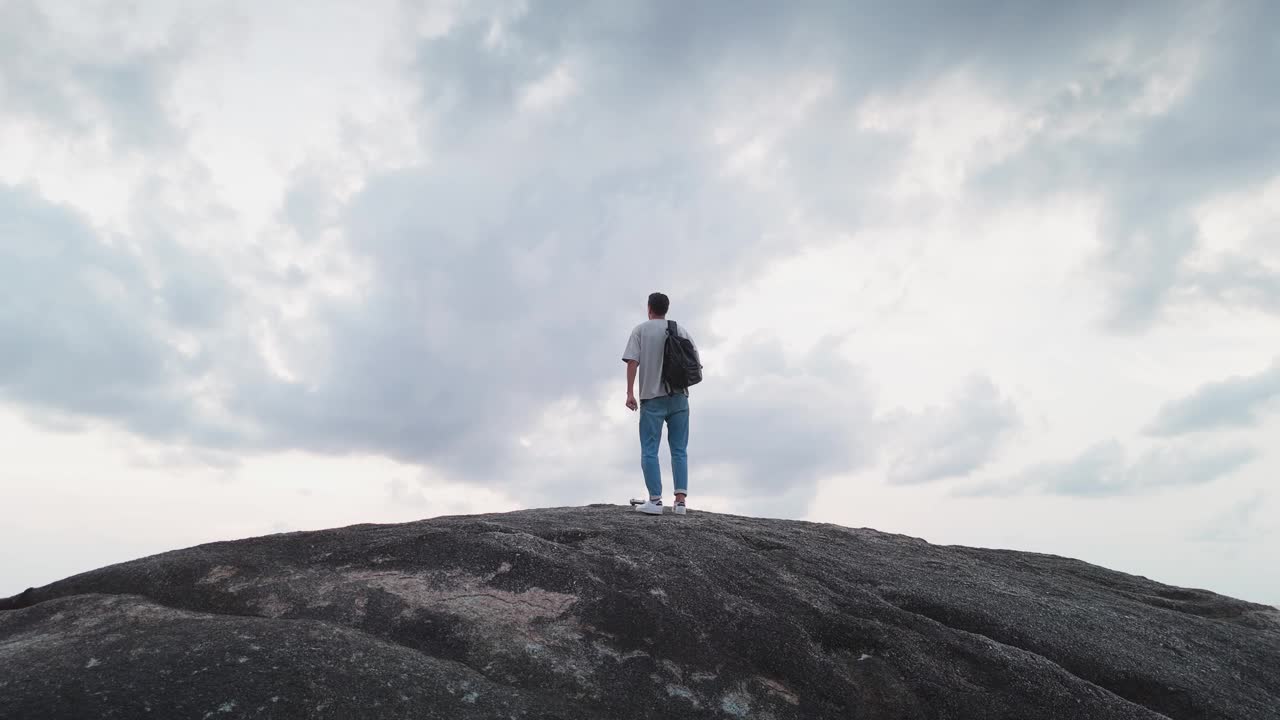 游客在到达山顶时欢欣鼓舞，高兴地跳起来，向天空伸出手。背影映衬着一望无际的蓝天。在群山之上的广阔天空下快乐的游客。视频素材