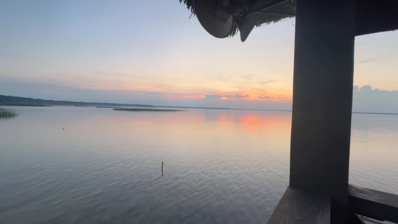 木屋里宁静的夕阳映在宁静的湖面上视频下载