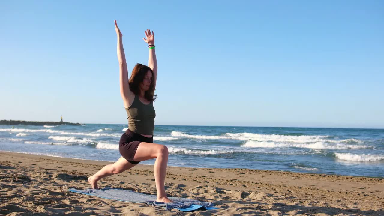 美丽苗条的年轻女子在海滩上做莲花体式瑜伽，海浪的声音视频下载