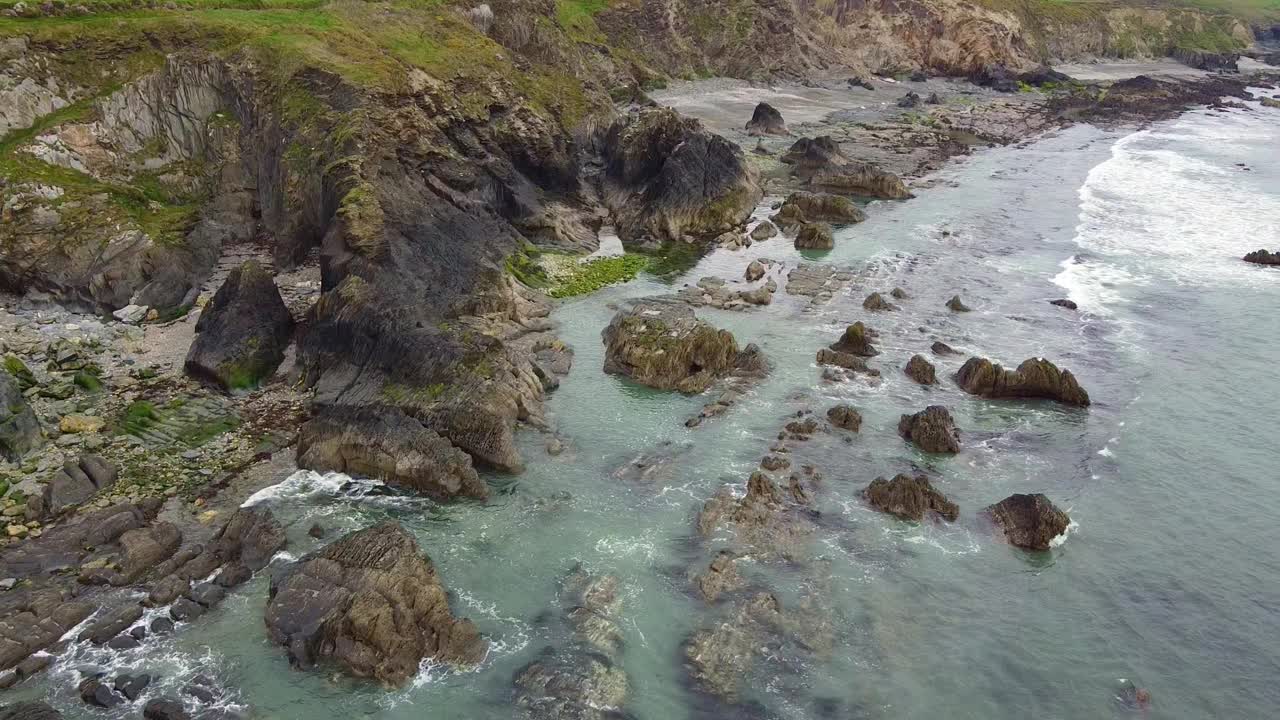 多岩石的海岸线和沙滩，海浪拍打着岩石。视频素材