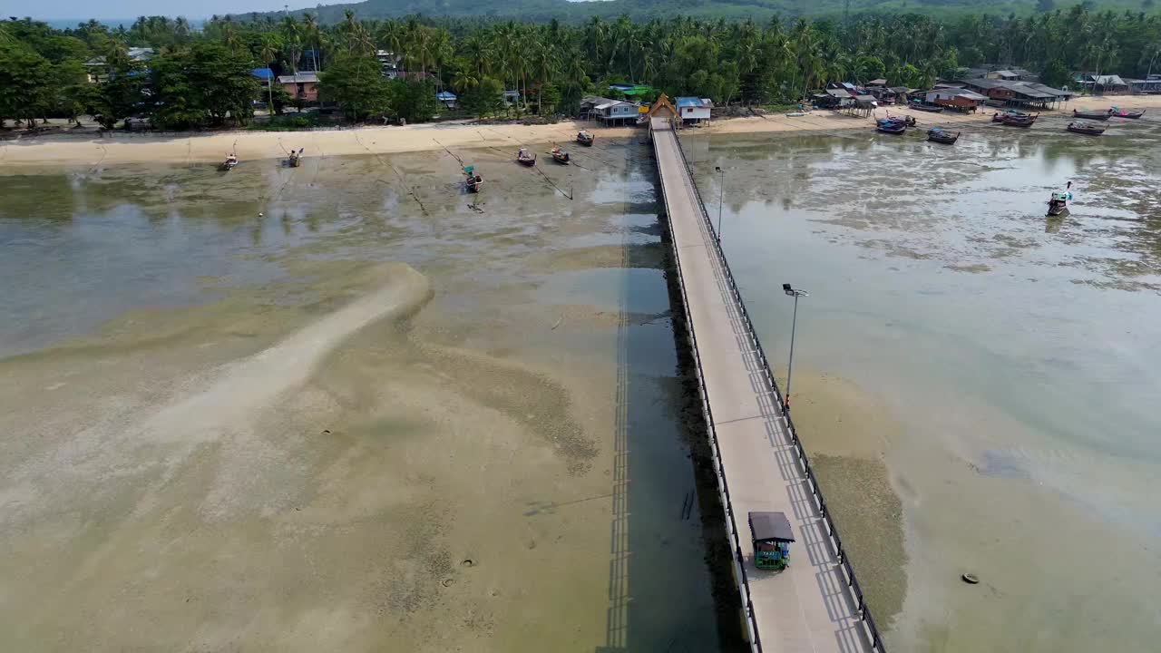 鸟瞰图:一辆黄包车沿着木岛码头行驶，背景是森林景观，泰国董里岛视频下载