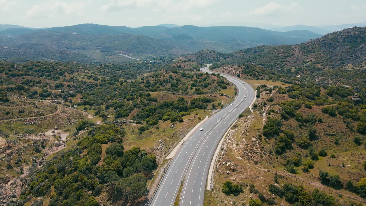 汽车行驶在高速公路在山上穿过绿色的丘陵山谷视频素材