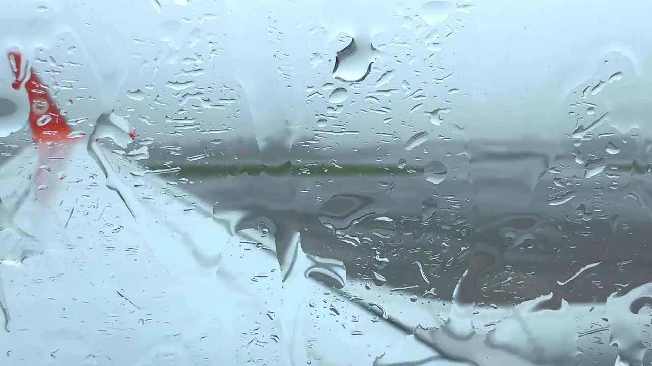 一个下雨天，一架飞机停在泰国普吉岛机场的停机坪上，雨滴顺着飞机的窗户流下来视频素材