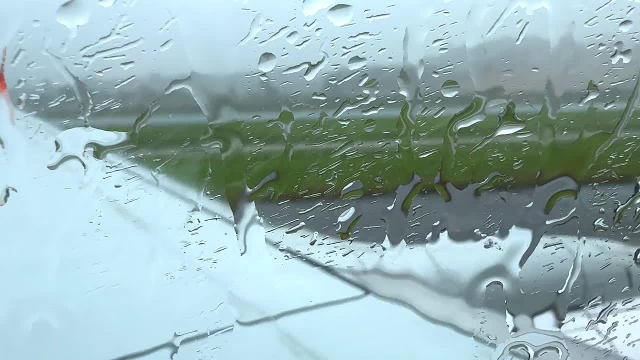 一个下雨天，一架飞机停在泰国普吉岛机场的停机坪上，雨滴顺着飞机的窗户流下来视频下载