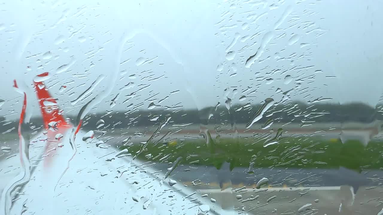 一个下雨天，一架飞机停在泰国普吉岛机场的停机坪上，雨滴顺着飞机的窗户流下来视频下载