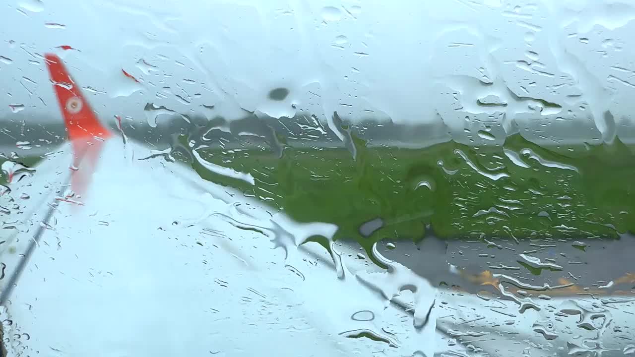 一个下雨天，一架飞机停在泰国普吉岛机场的停机坪上，雨滴顺着飞机的窗户流下来视频下载