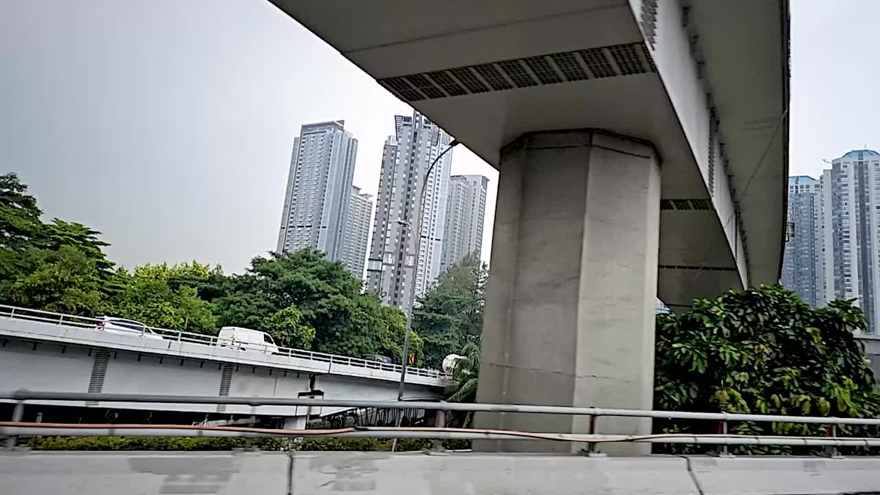 在一个阳光明媚的日子里，沿着印度尼西亚首都雅加达的主要道路大道，开车穿过现代化的雅加达商业区视频下载