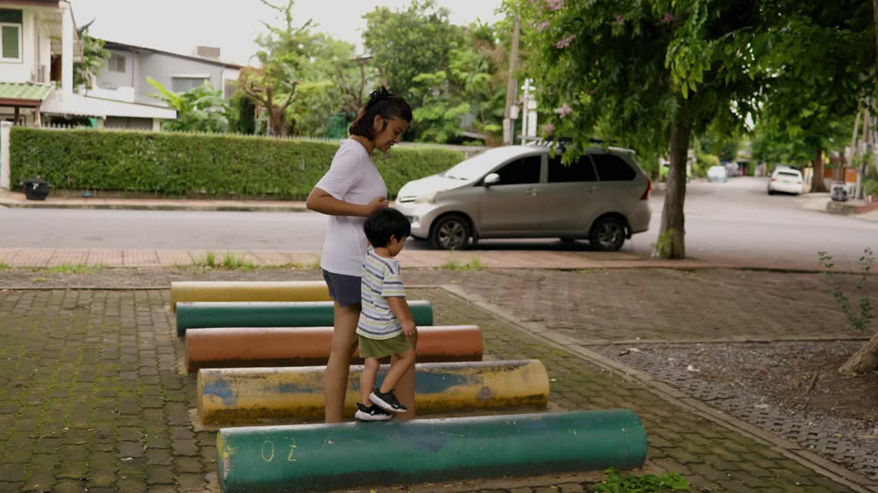 一位亚洲母亲带着她的儿子走上一条陡峭的道路，练习平衡和冒险。视频素材