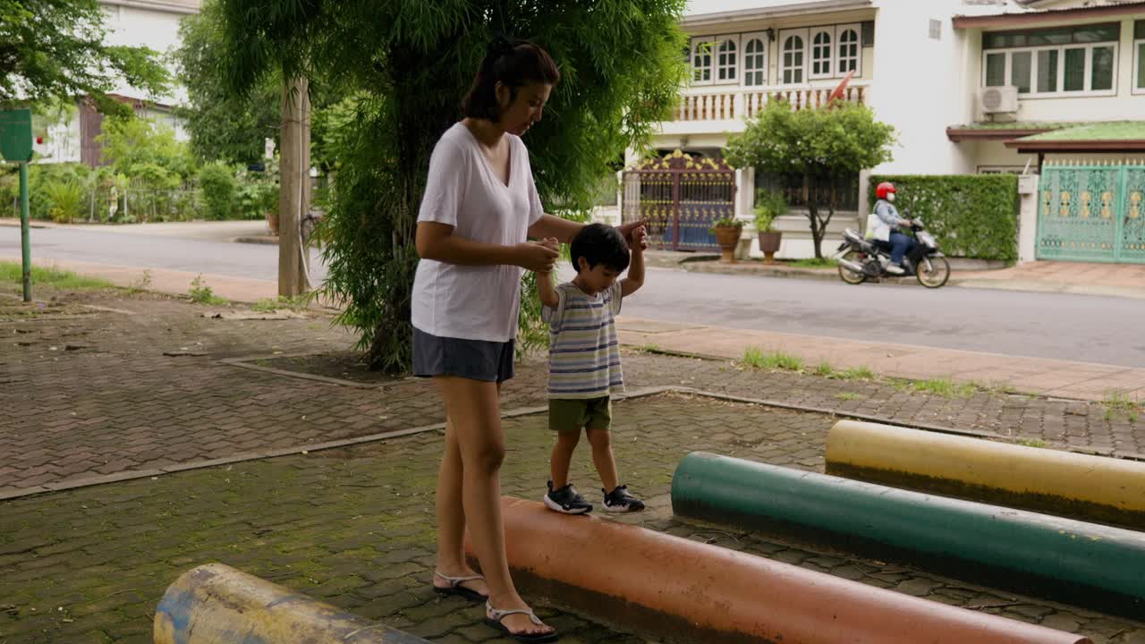 一位亚洲母亲带着她的儿子走上一条陡峭的道路，练习平衡和冒险。视频素材