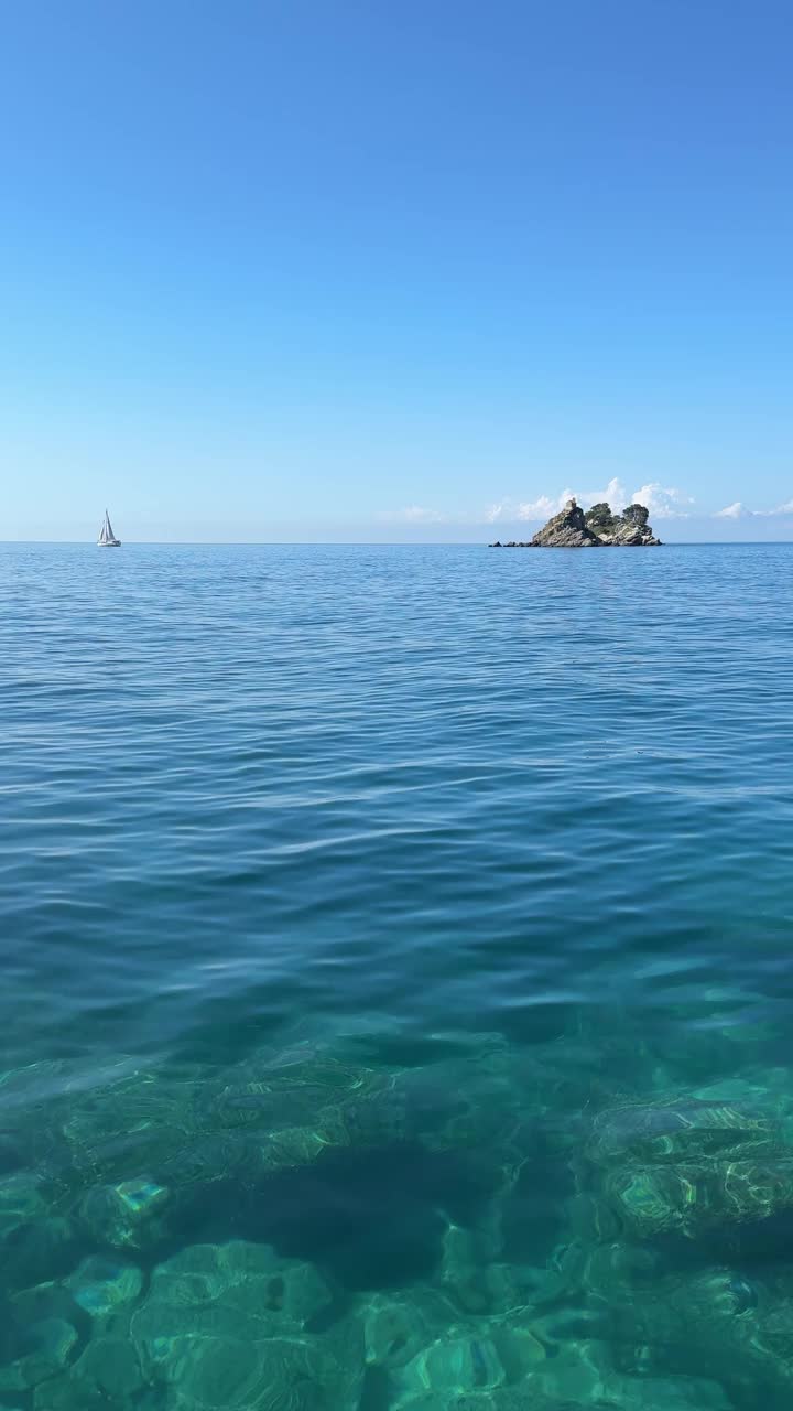 蓝色的大海，岩石，帆船，垂直视频。视频素材