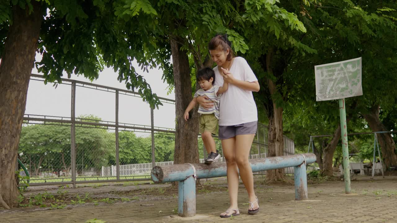 一位亚洲母亲带着她的儿子走上一条陡峭的道路，练习平衡和冒险。视频素材