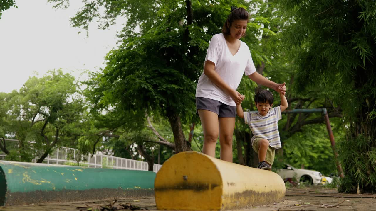 一位亚洲母亲带着她的儿子走上一条陡峭的道路，练习平衡和冒险。视频素材