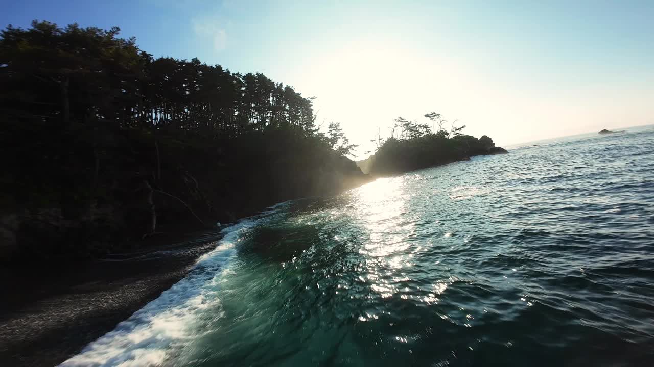 黎明时分，一架低矮的FPV飞机飞过岩石嶙峋的雄伟海岸线上的一顶帽子视频素材