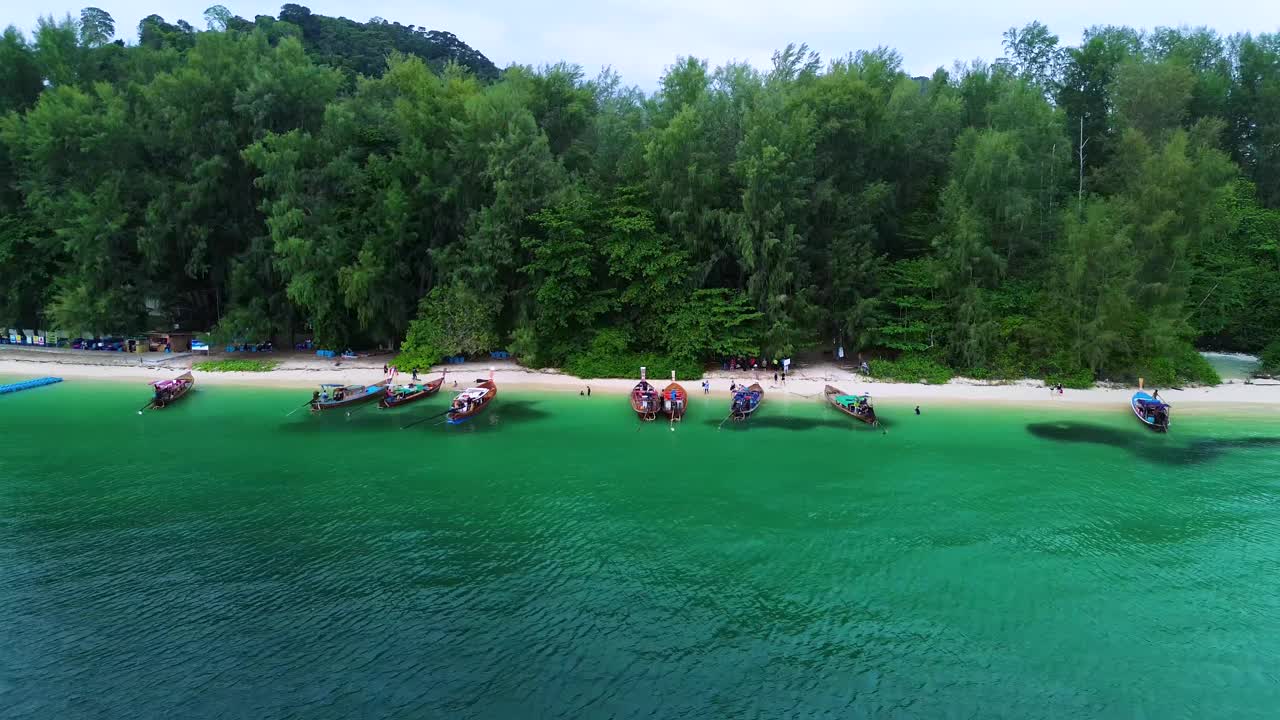 长尾游船停泊在Koh Kradan，人们沿着海滩散步。Koh Kradan，泰国中岛。视频下载