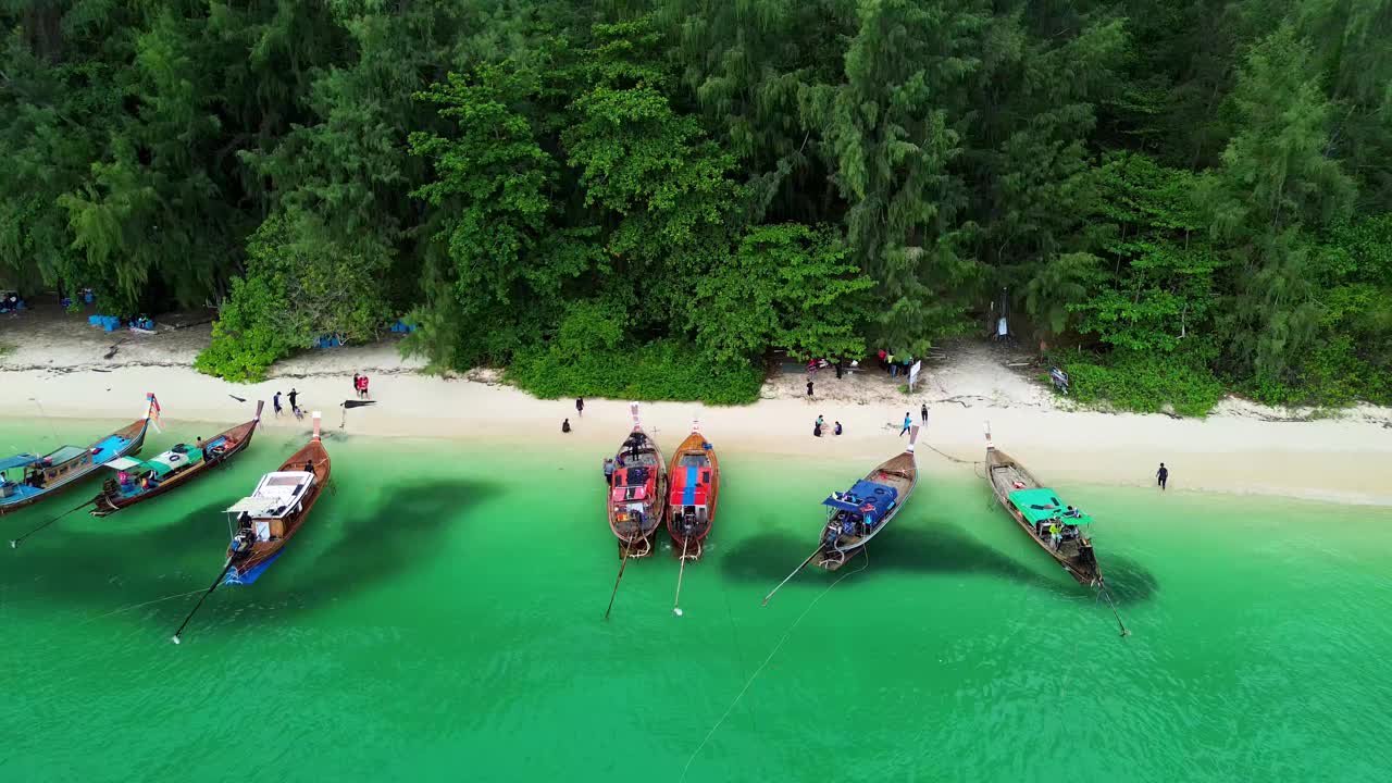 长尾游船沿着Koh Kradan停泊，鱼群聚集在水面上。Koh Kradan，泰国中岛。视频下载