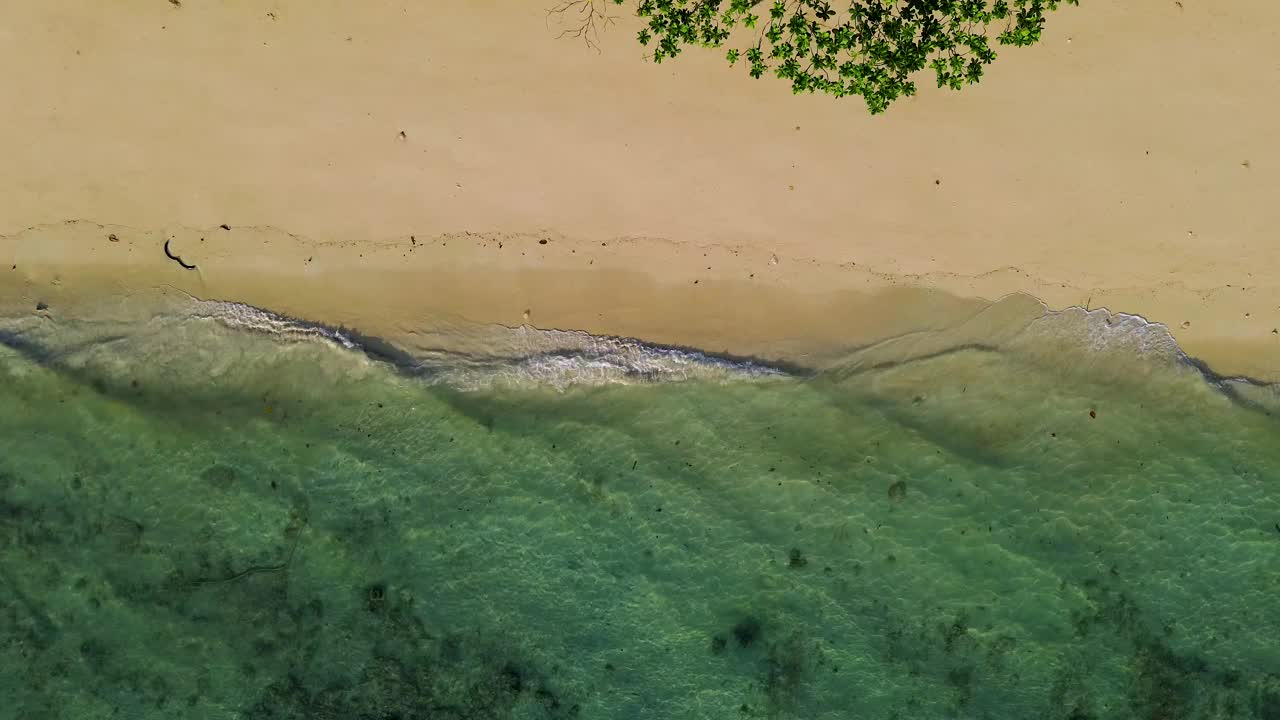 假日白色沙滩的鸟瞰图，清澈的海水和海浪在沙滩上翻滚。泰国视频下载