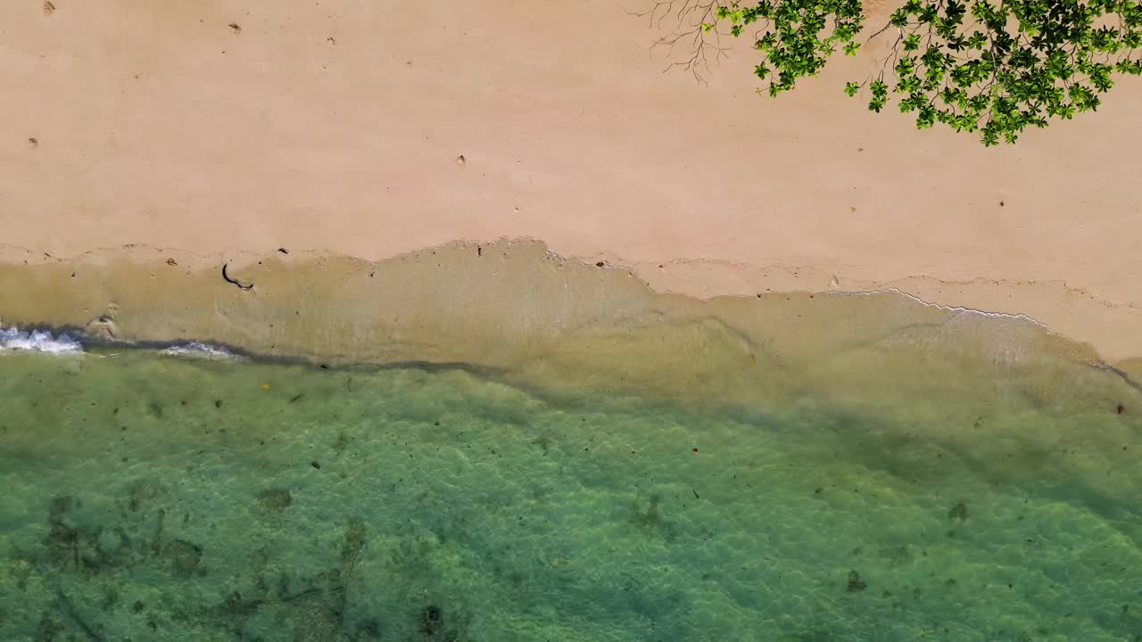 假日白色沙滩的鸟瞰图，清澈的海水和海浪在沙滩上翻滚。泰国视频下载