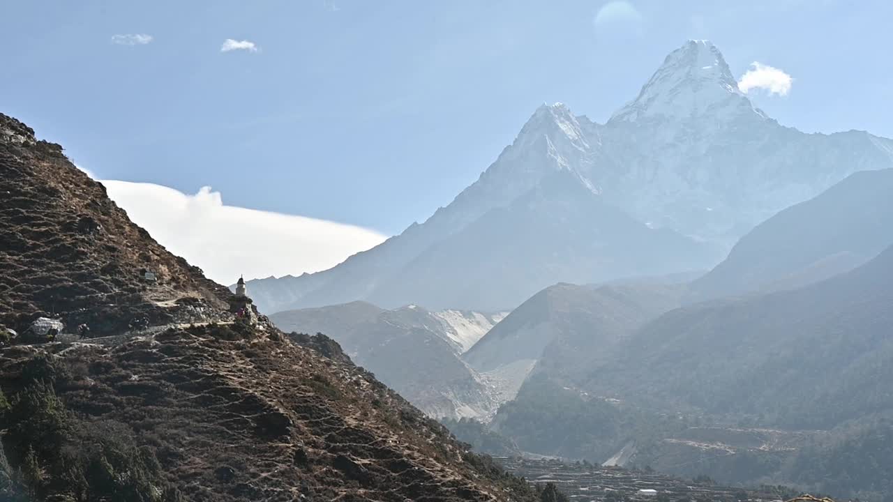 徒步旅行者在山边行走的镜头，背景是ama Dablam山的美丽景色。视频下载