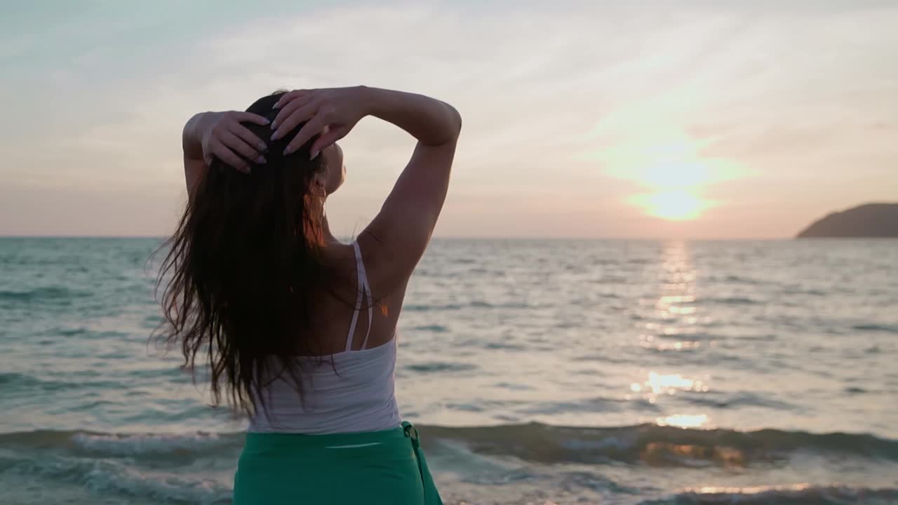 女人在有风的日子里一边玩头发一边欣赏海景视频素材