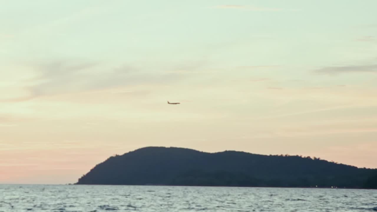 日落时飞机在海上和山上飞行的景象视频下载