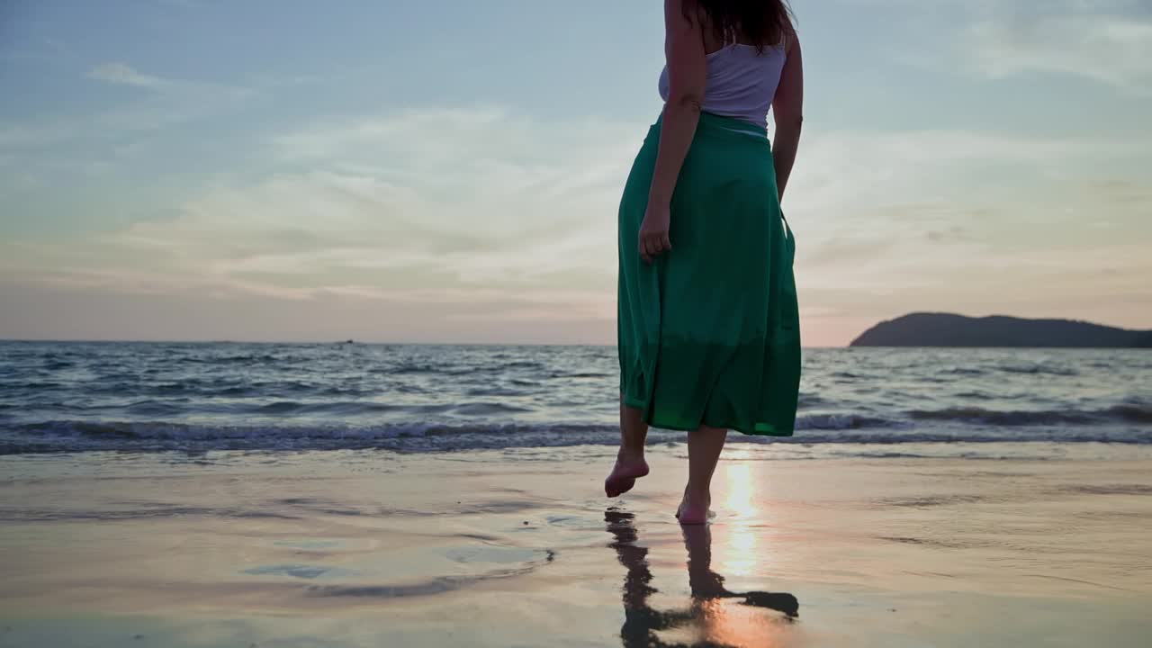 日落时分，一名女子赤脚走在沙滩上视频素材