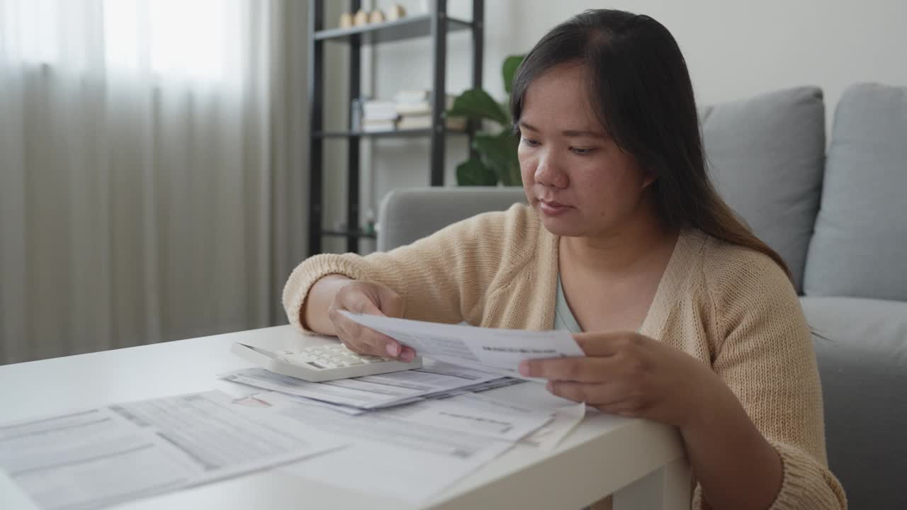 亚洲妇女用计算器计算家庭财务账单视频素材