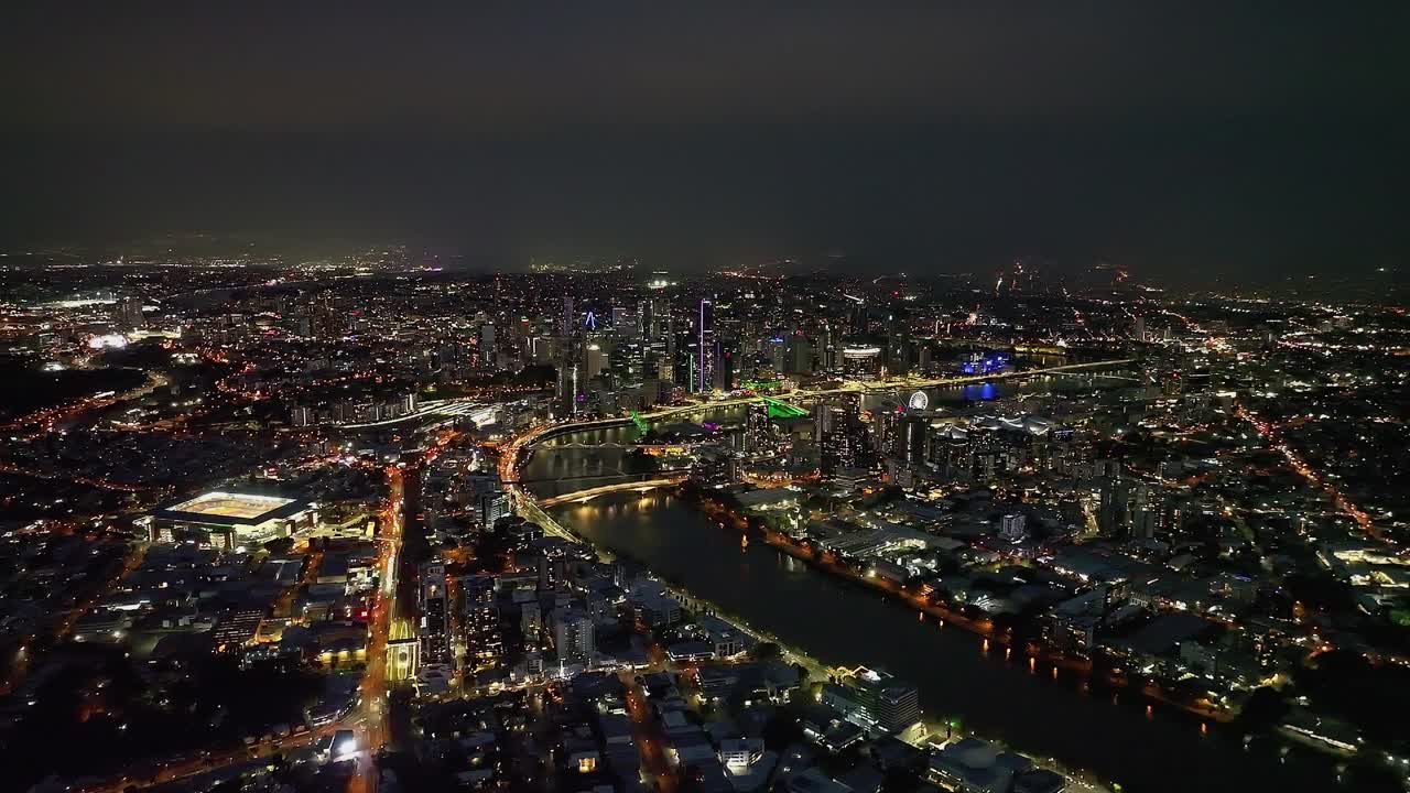 航拍视频来回移动，同时显示布里斯班河和周围的城市景观在晚上，昆士兰，澳大利亚视频素材