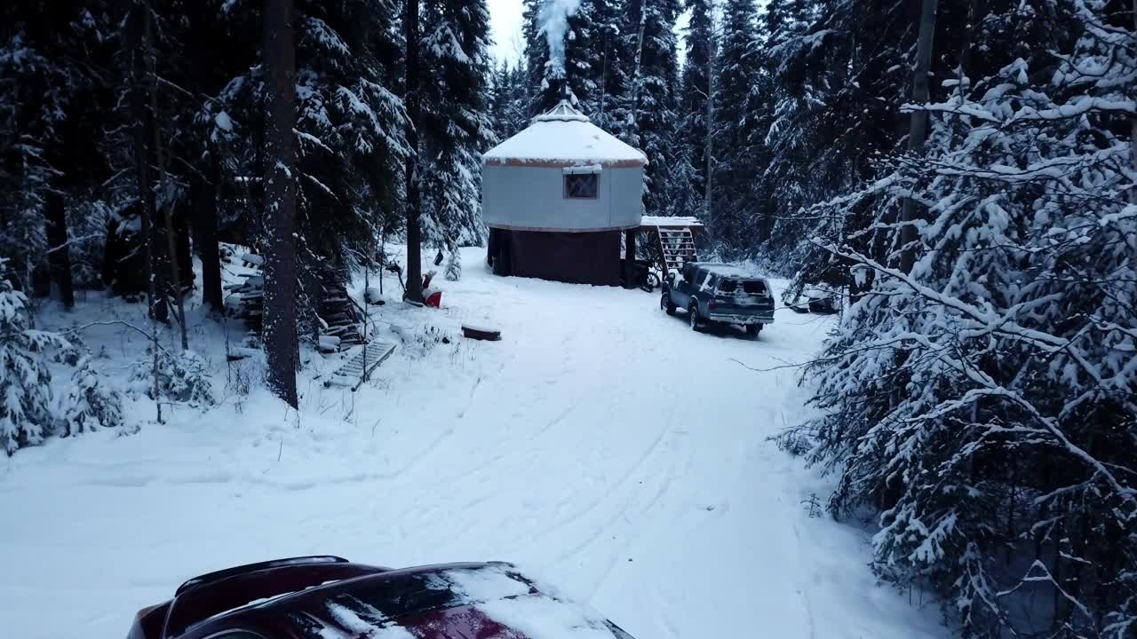 航拍:无人机以色利前进党拍摄的人在积雪覆盖的宁静森林里走上小木屋的台阶-阿拉斯加的德纳里国家公园视频下载