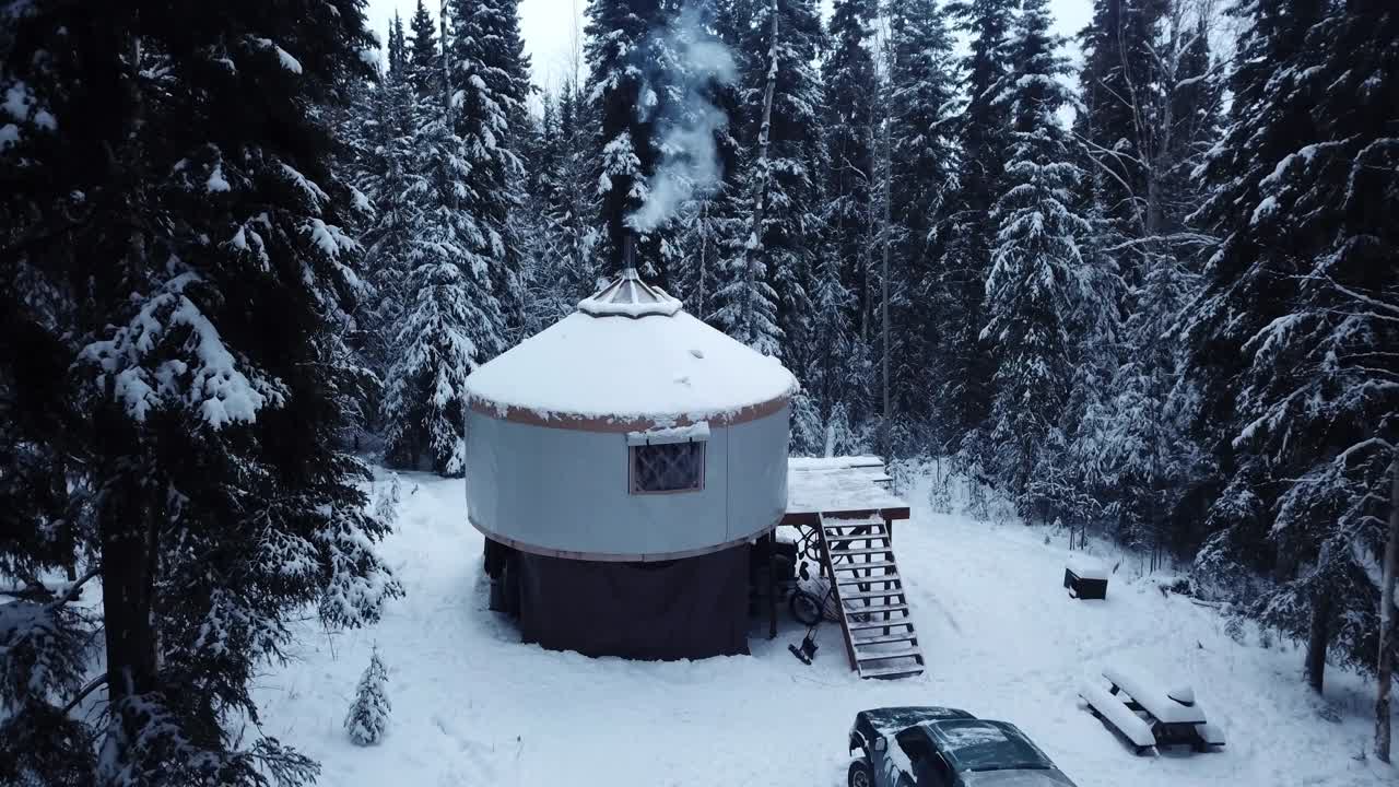 航拍:无人机锁定白雪覆盖的汽车和木屋在森林在雪季-德纳里国家公园，阿拉斯加视频下载