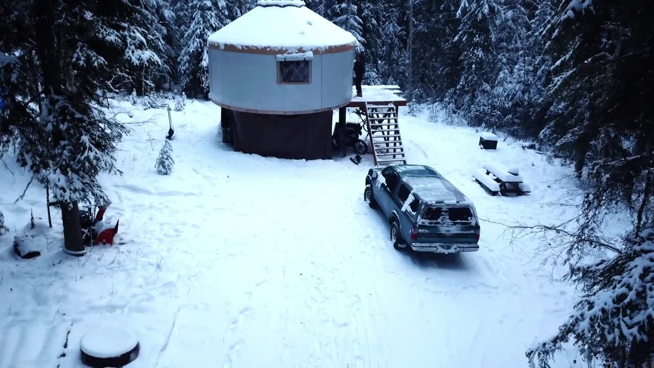 航拍:无人机在冬季在冷杉林中的雪覆盖的小木屋中拍摄的人-德纳里国家公园，阿拉斯加视频下载