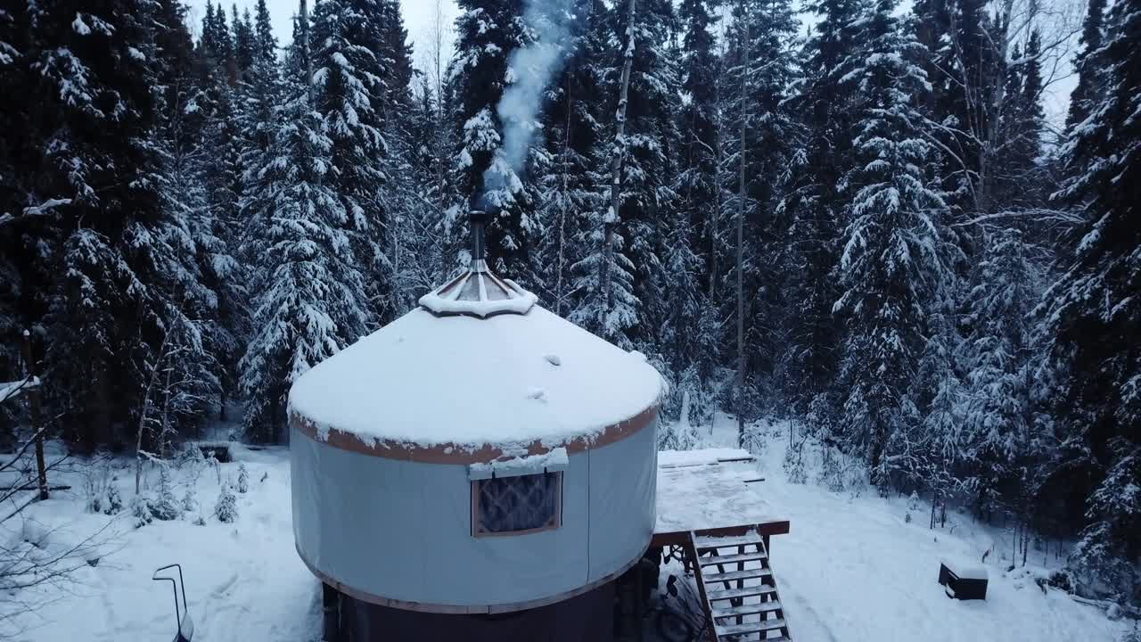 航拍:阿拉斯加德纳里国家公园，森林里积雪覆盖的小木屋的无人机锁定镜头视频下载