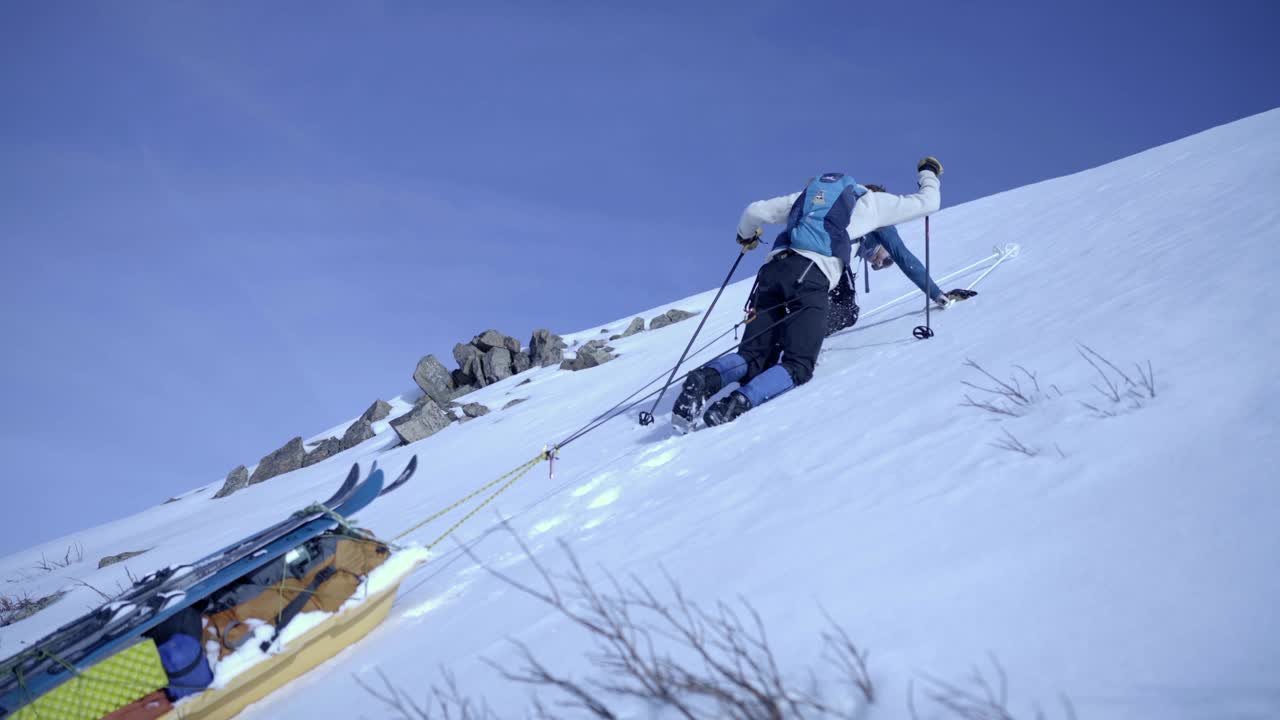 在阳光明媚的日子里，人们在雪坡上拉雪橇的锁定镜头——阿拉斯加的德纳里国家公园视频下载