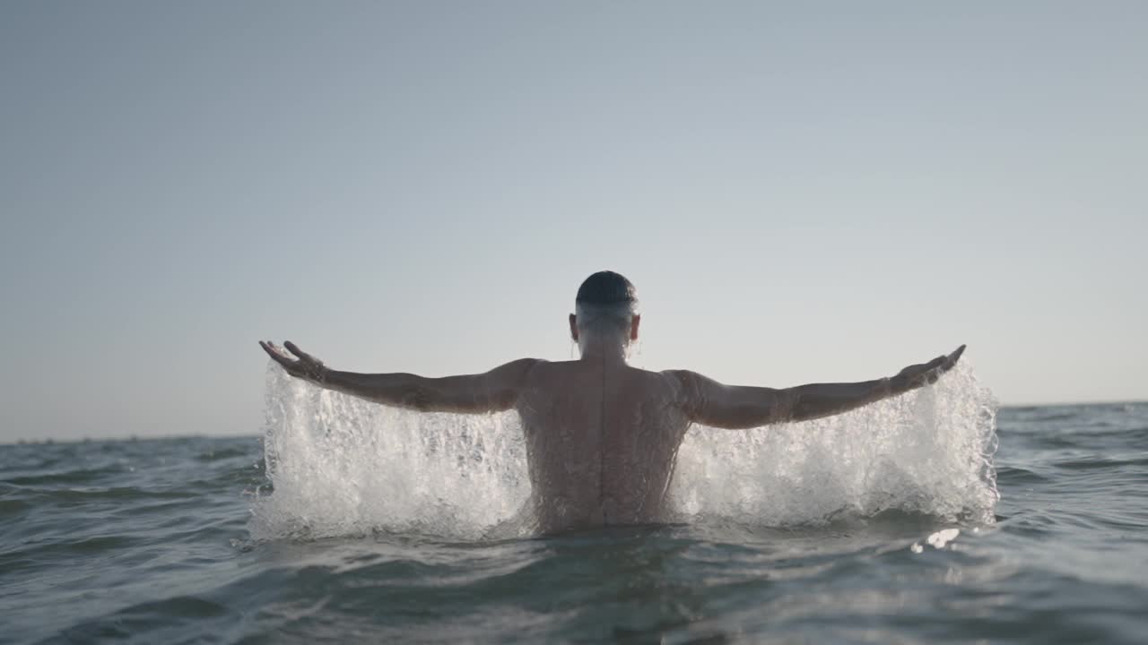 一个男人在美丽的日落时分拥抱海浪视频素材