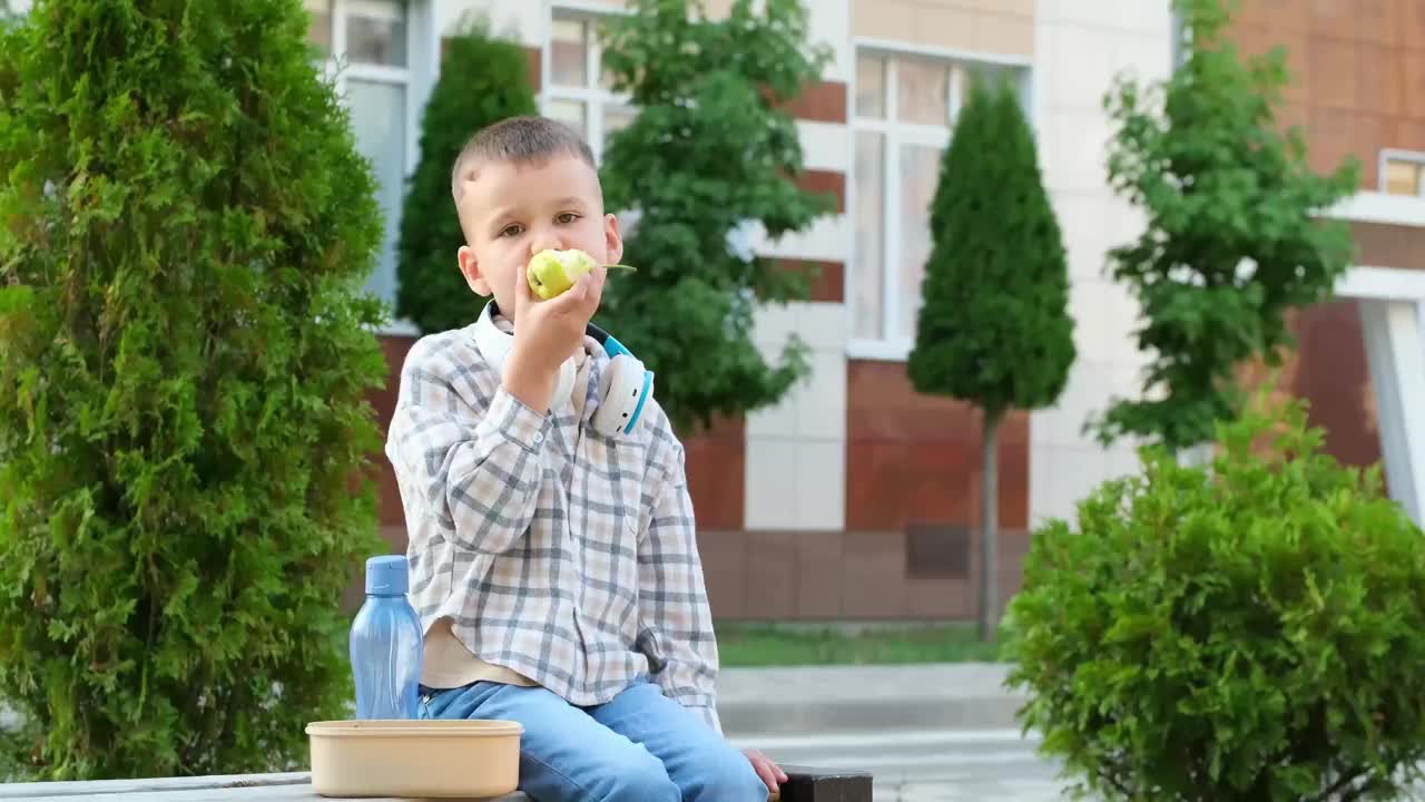 学校餐，一个学生的孩子在街上吃午饭，一个男孩在上学前吃三明治，一个学生的快餐。视频下载